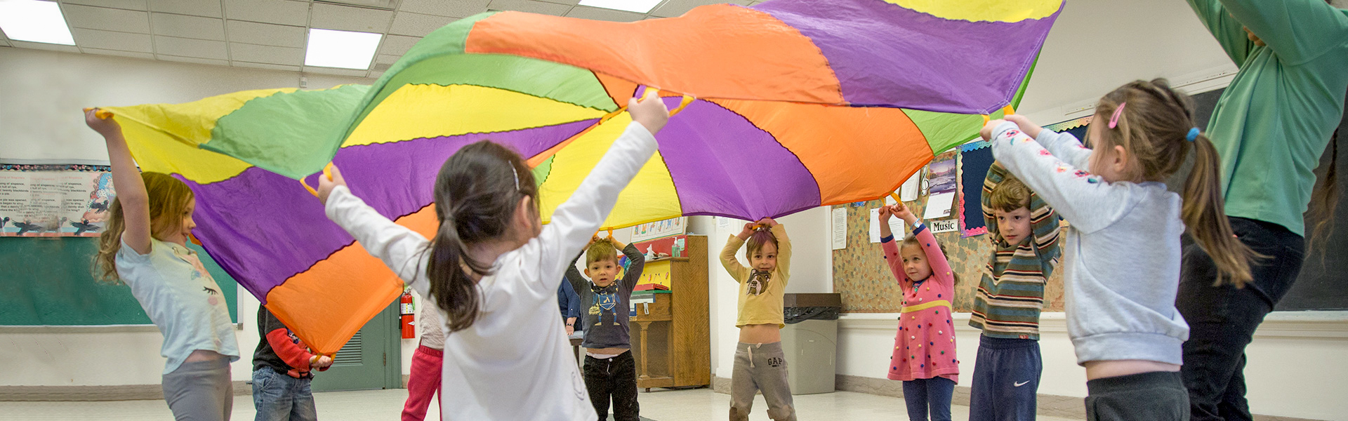 young kids playing with a parachute at school
